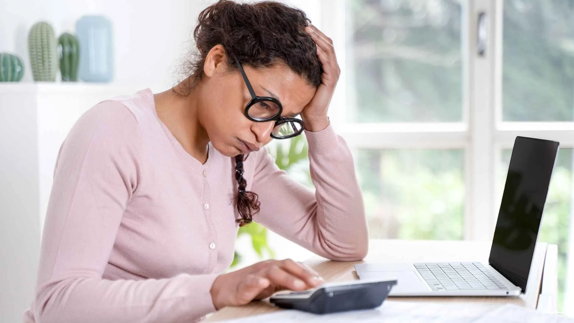 Worried woman calculating her finances at home