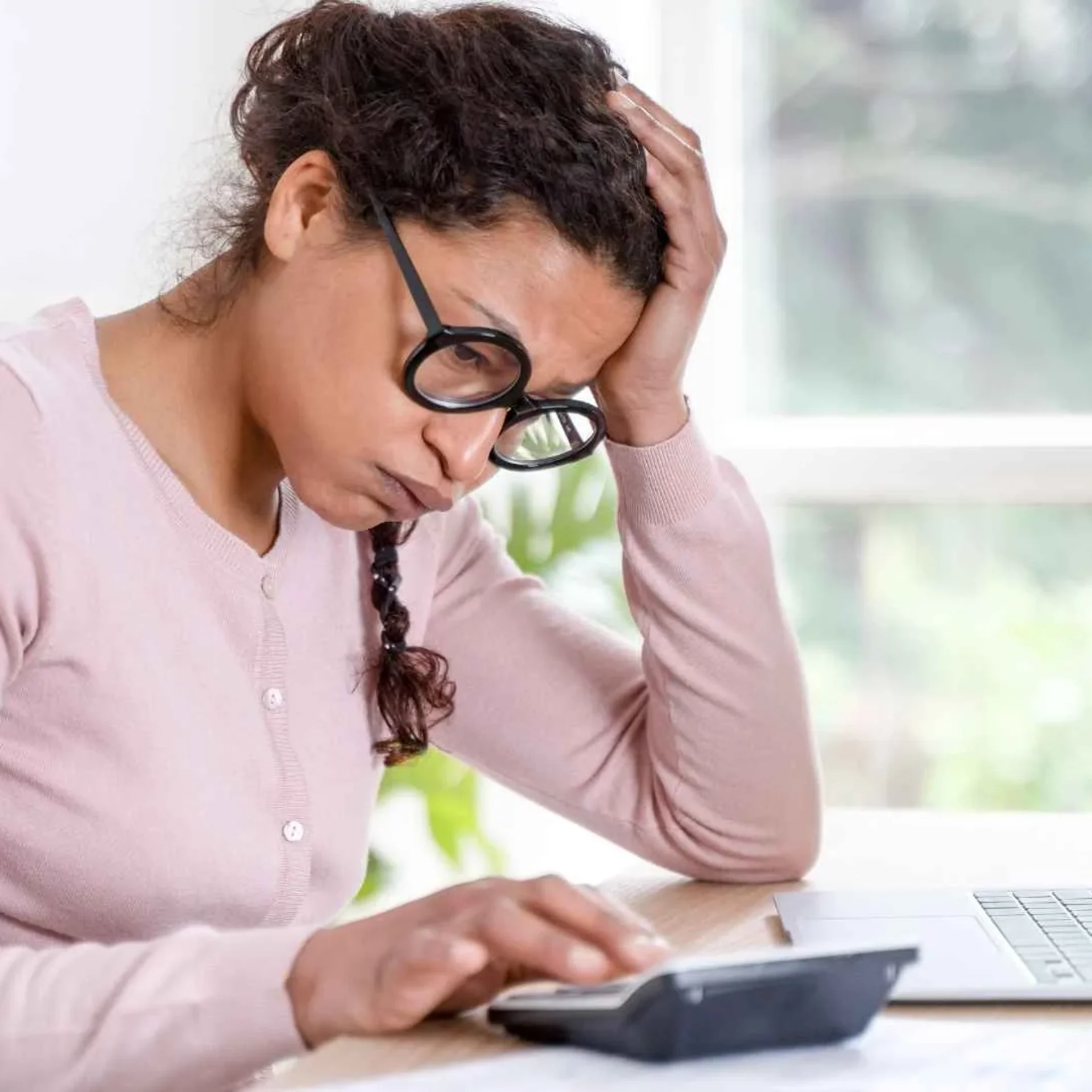 Managing Debt Stress – Financial Planning at Home Worried woman calculating her finances at home